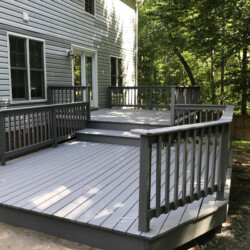 Multi-level gray wooden deck attached to a gray house.