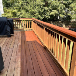 Wooden deck showing a clear contrast between the unfinished section and the freshly stained portion.