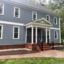 Two-story blue house with white trim, a covered front porch, and a stone walkway.