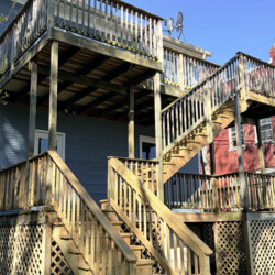 A multi-level wooden deck with stairs attached to the back of a house.