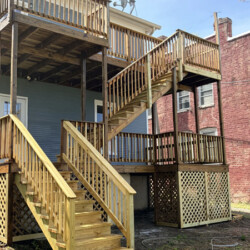 A multi-level wooden deck and staircase attached to the back of a house.