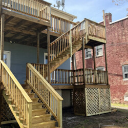 A multi-level wooden deck with stairs attached to the back of a house.