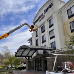 A worker in a lift basket repairing the SpringHill Suites hotel sign.