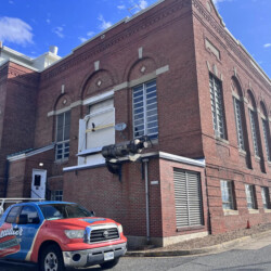 A Bluewater Powerwashing truck parked in front of a multi-story brick building.
