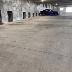 A blue sedan parked in a mostly empty concrete parking garage.