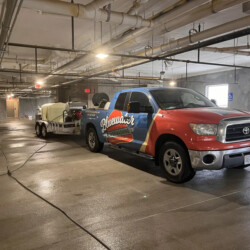 Bluewater Powerwashing truck and trailer parked in an underground parking garage.