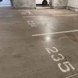 Empty parking spots numbered 233, 234, and 235 in a concrete garage.