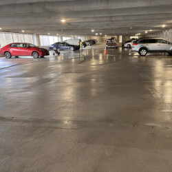 A wet, empty parking garage with several parked cars.