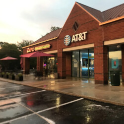 A brick storefront featuring an AT&T store and Zara Mediterranean Charcoal Grill with outdoor seating.