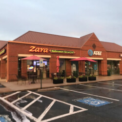A brick strip mall with storefronts for Zara Mediterranean Charcoal Grill, AT&T, and Smoothie King.