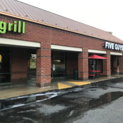 Storefronts for Mac’s Speed Shop and Five Guys in a brick strip mall.