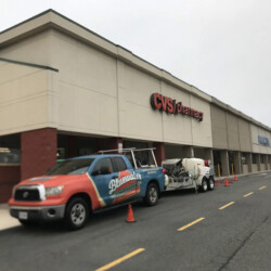 A Bluewater Power Washing truck pulling a trailer is parked in front of a CVS Pharmacy.