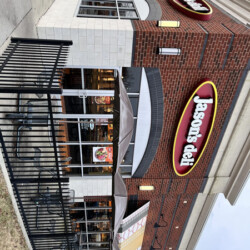 Exterior view of a Jason’s Deli restaurant with brick walls, an outdoor patio, and branded signage.