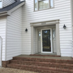 White house exterior with a front door numbered 12001 and brick front steps.