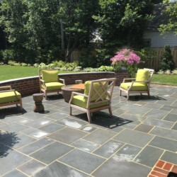 Four lime green patio chairs arranged around a small table on a stone terrace.