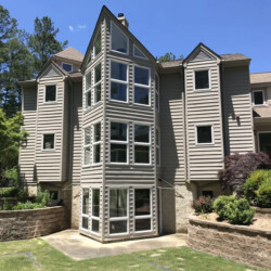A multi-story house with beige siding and a tall, triangular window projection.