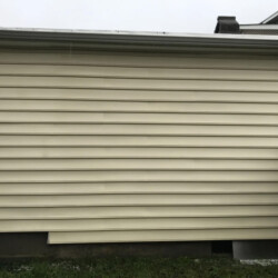 Exterior wall of a house with cream-colored horizontal siding and a white gutter.